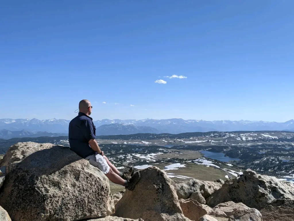 Bryan sitting on a mountain top