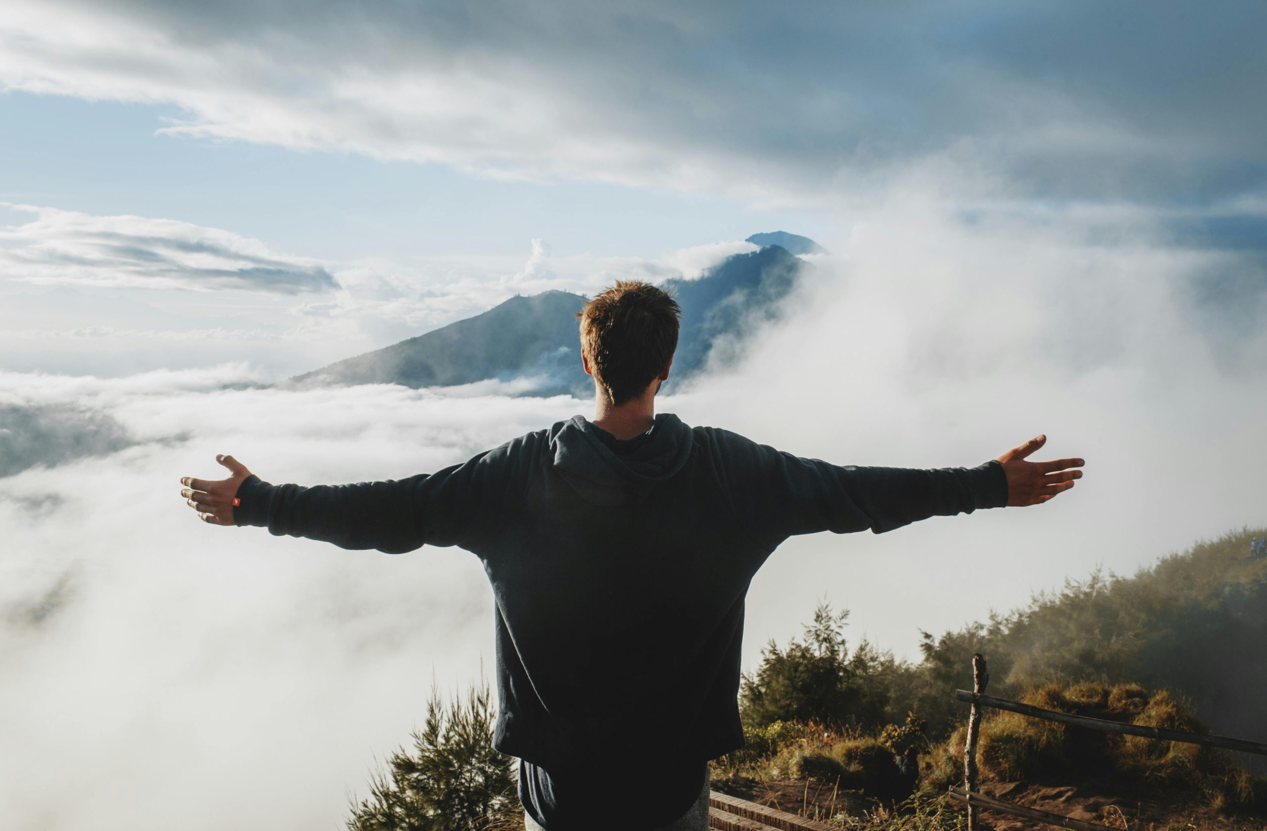 Photo by ROMAN ODINTSOV: Man with arms outstretched admiring view- from mountain cliff